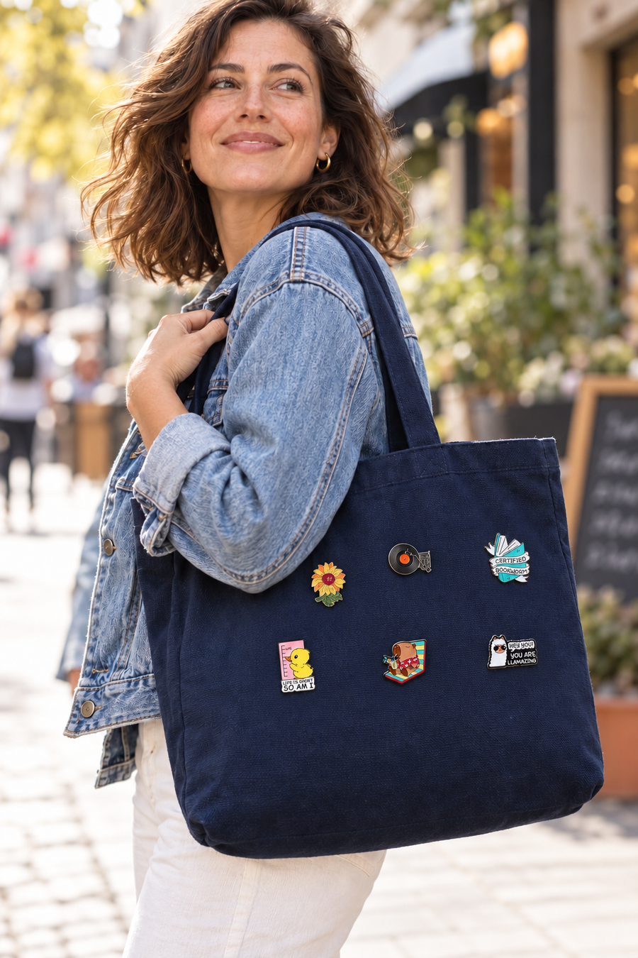 Illustratief sfeerbeeld: vrouw met een donkerblauwe tas met zes kleine Fasola-pins